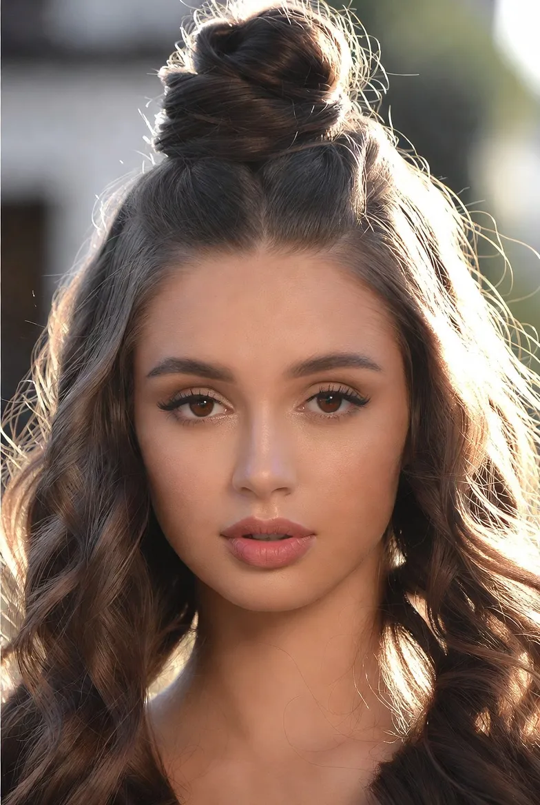 Mlada ženska s polovično speto figo in valovitimi rjavimi lasmi za pomladno svežino